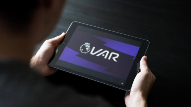  A person looking at VAR on their tablet during a football match